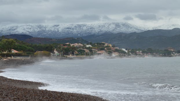 Misty winter coastal view of Saint-Florent, Corsica with snowy mountains.