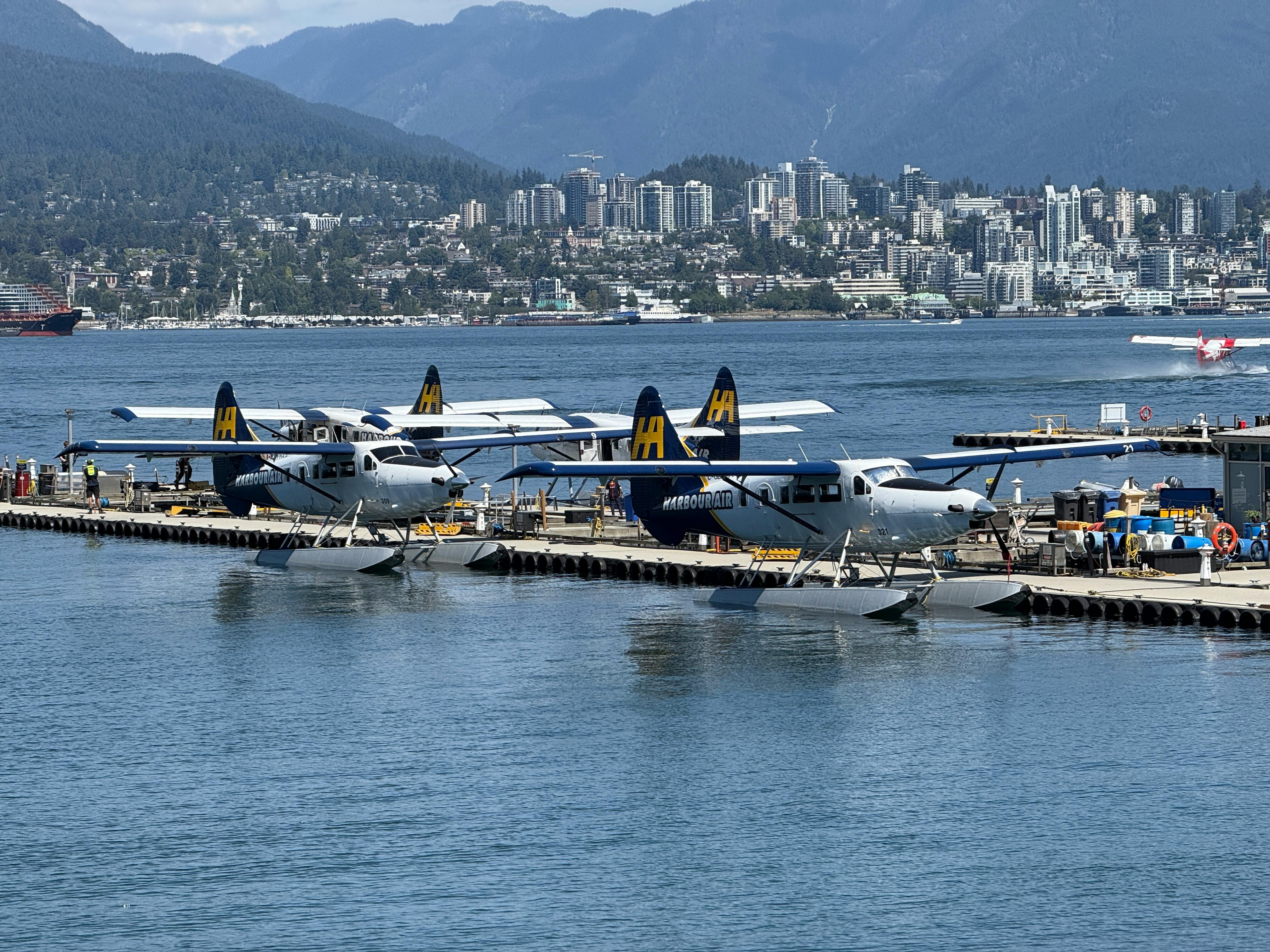 Seaplanes docked at Vancouver waterfront with city skyline in background. - Vancouver