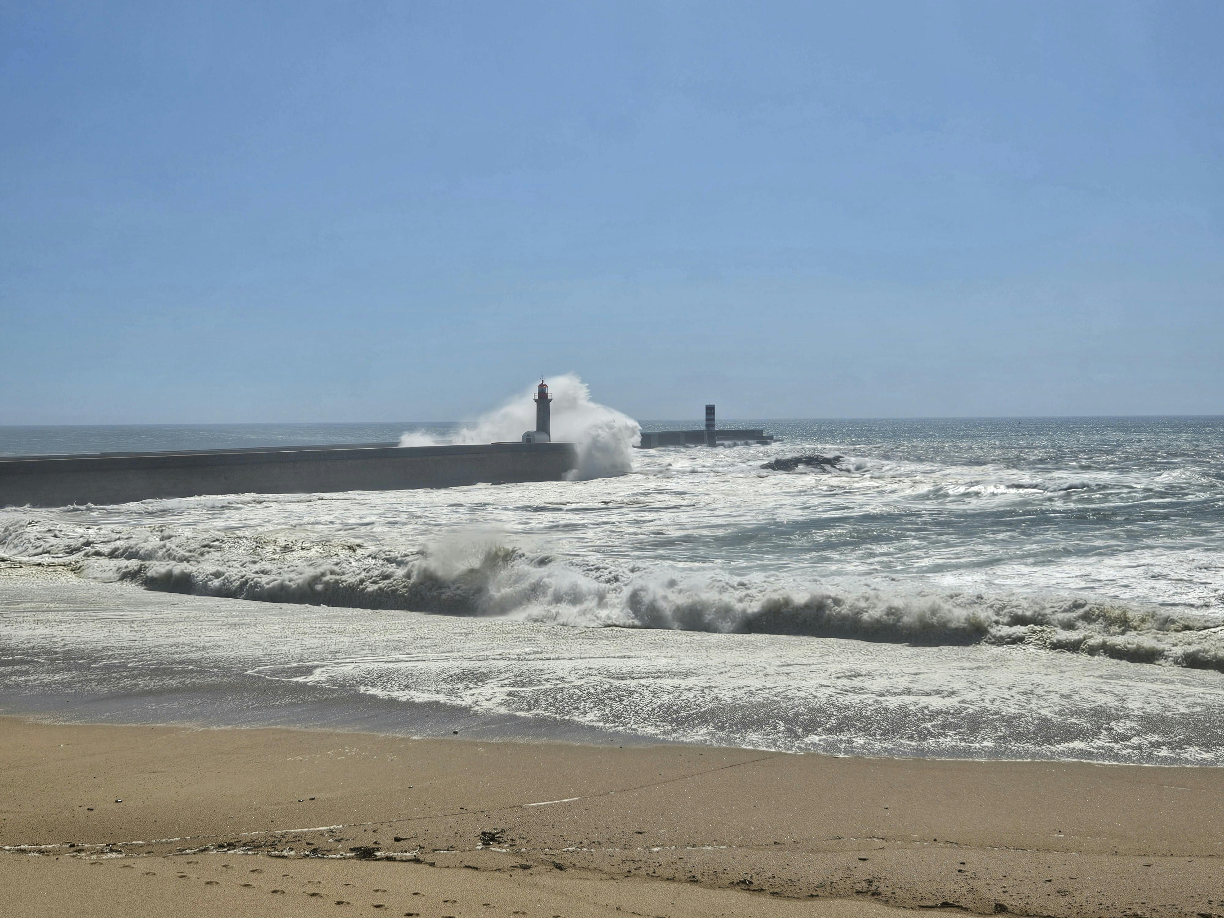 Stunning view of waves crashing against the lighthouse in Porto, Portugal.