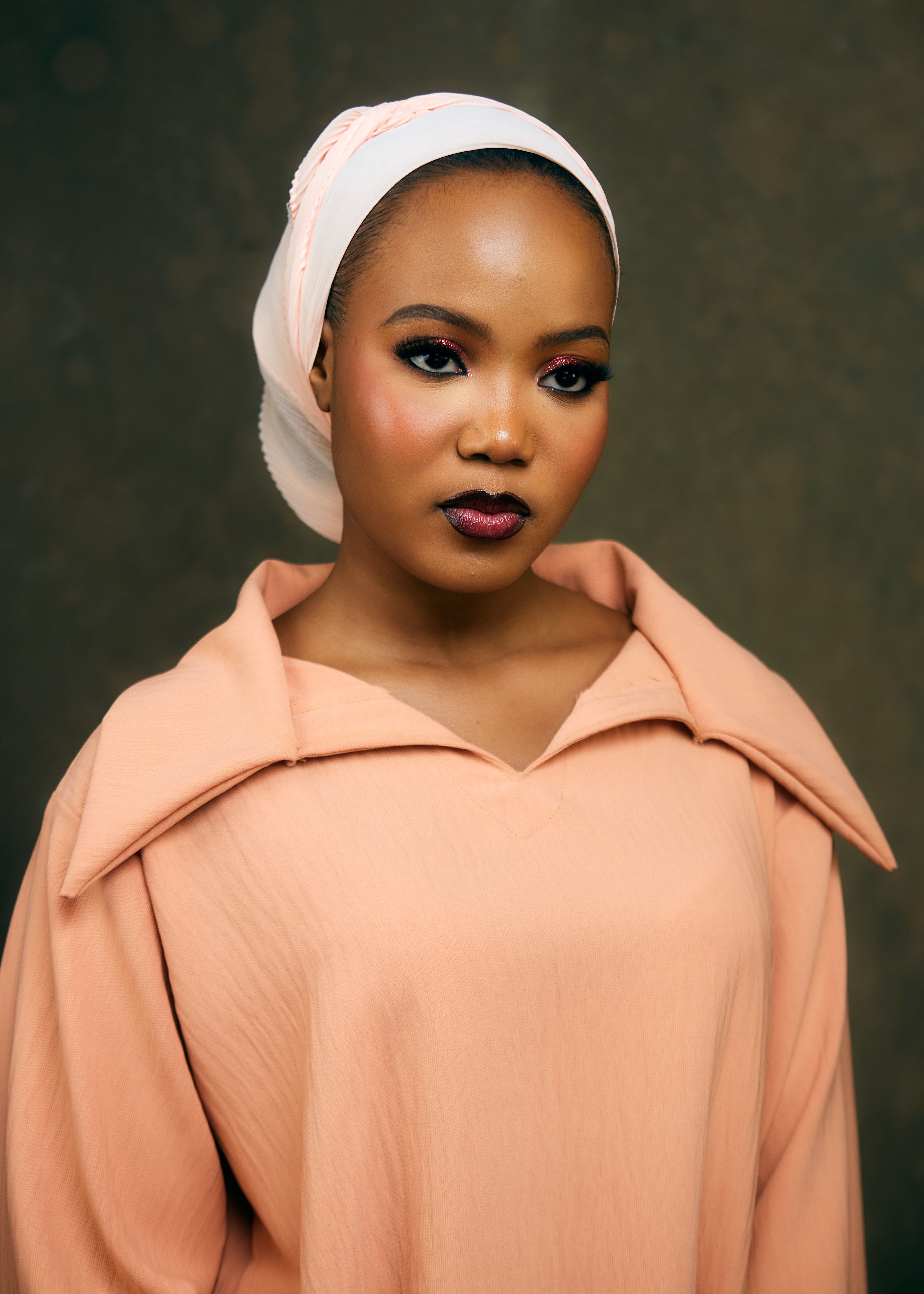 Stylish portrait of a woman in a peach outfit with a white hijab. Elegant and poised.