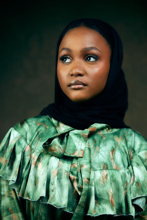 Free Elegant portrait of a woman wearing a stylish green outfit and black headscarf. Stock Photo