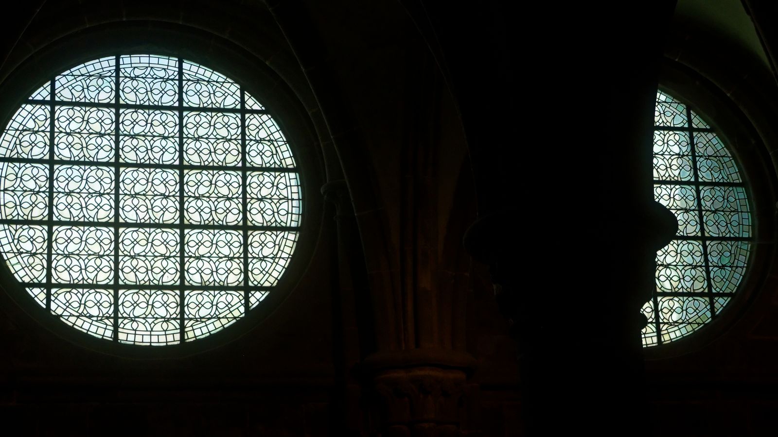 Baies rondes en grisaille et silhouette sombre d'une colonne dans une église