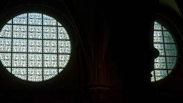 Baies rondes en grisaille et silhouette sombre d'une colonne dans une église