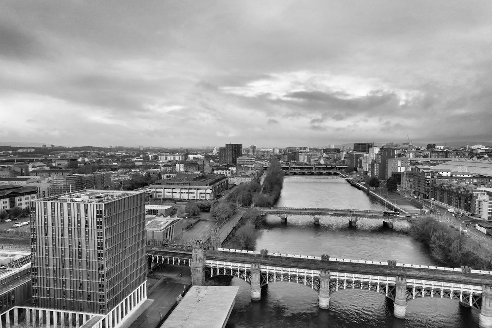 Black and white aerial cityscape of Glasgow featuring the River Clyde and surrounding architecture.