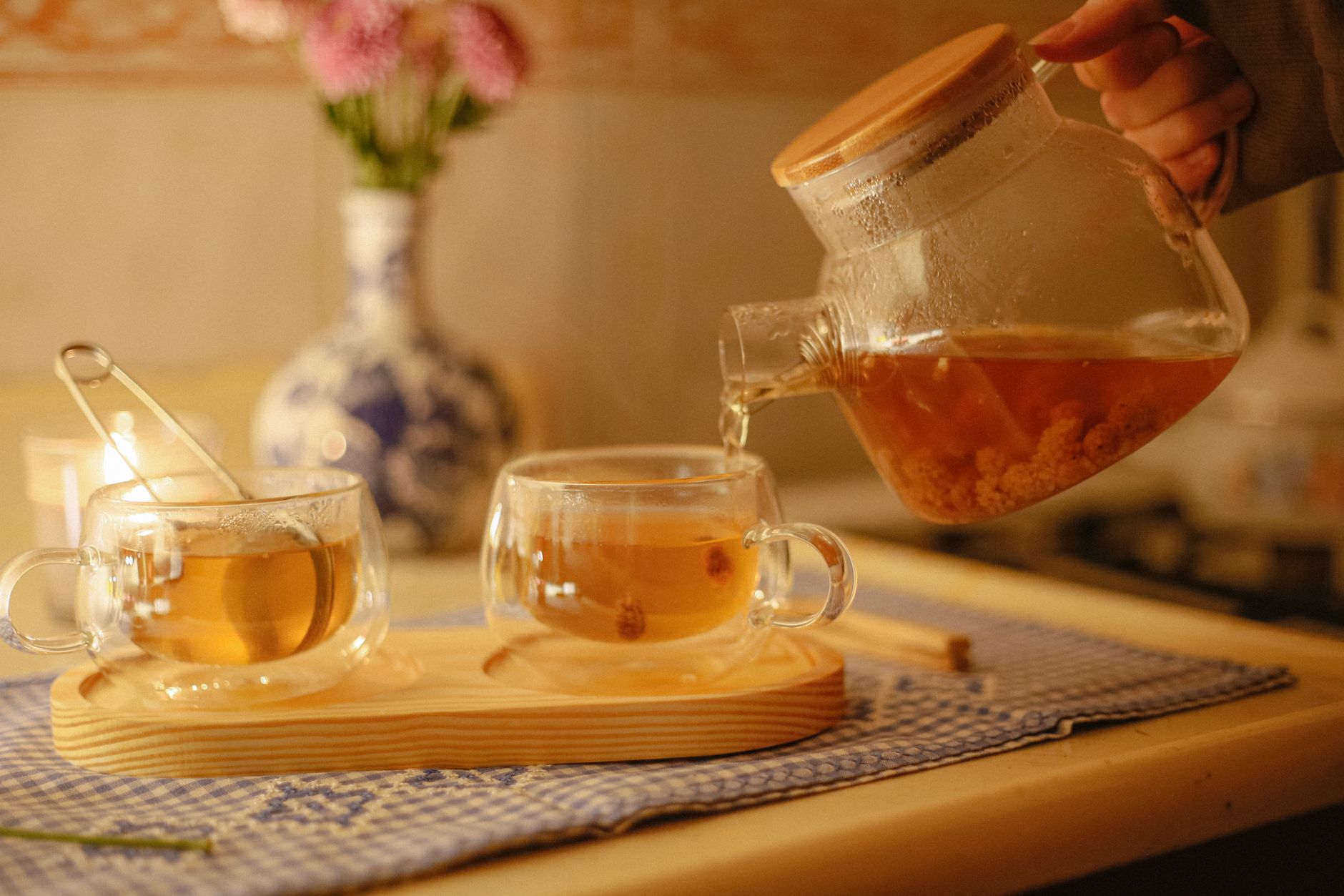trà kombucha dưỡng nhan - Một tách trà thảo mộc ấm với chanh, được phục vụ kèm táo và hồng trên khay gỗ.