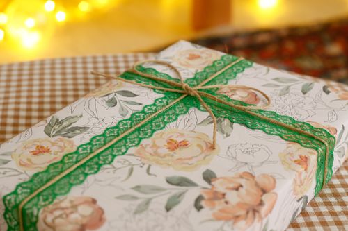 Free Beautifully wrapped floral gift box tied with green ribbon, perfect for celebrations. Stock Photo