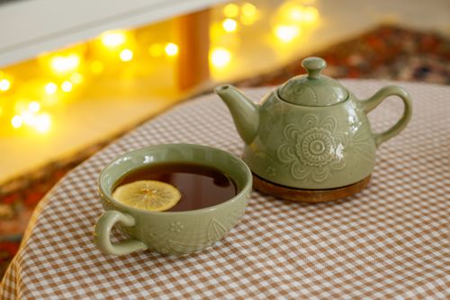 Free Green ceramic teapot and lemon-infused tea in a cozy indoor setting with warm lights. Stock Photo
