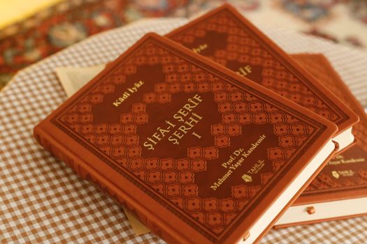 Close-up of traditional books with ornate covers on a checkered tablecloth, creating a vintage ambiance.