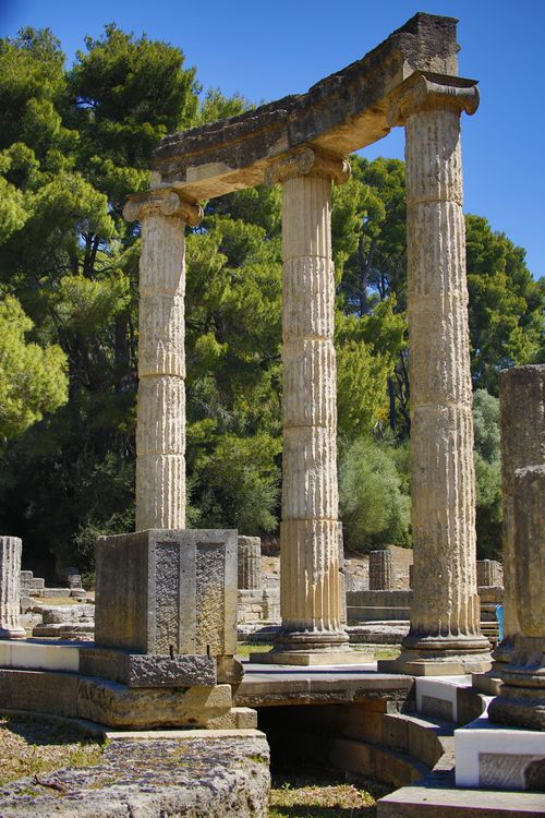 Free Ancient Greek columns under a clear blue sky, showcasing classical architecture amidst a lush, green landscape. Stock Photo