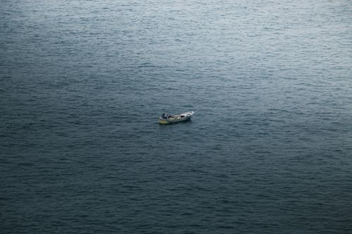 Free Small fishing boat drifting on the serene sea off Zonguldak, Türkiye, under a cloudy sky. Stock Photo