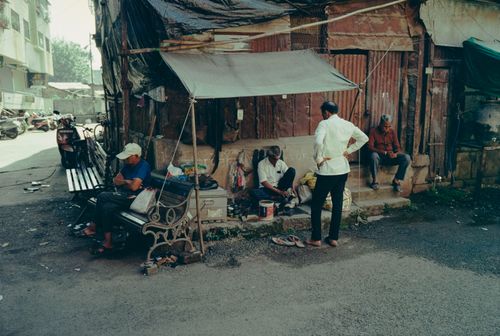 Free A candid moment on an Indian street showing people interacting with a shoe shiner. Stock Photo