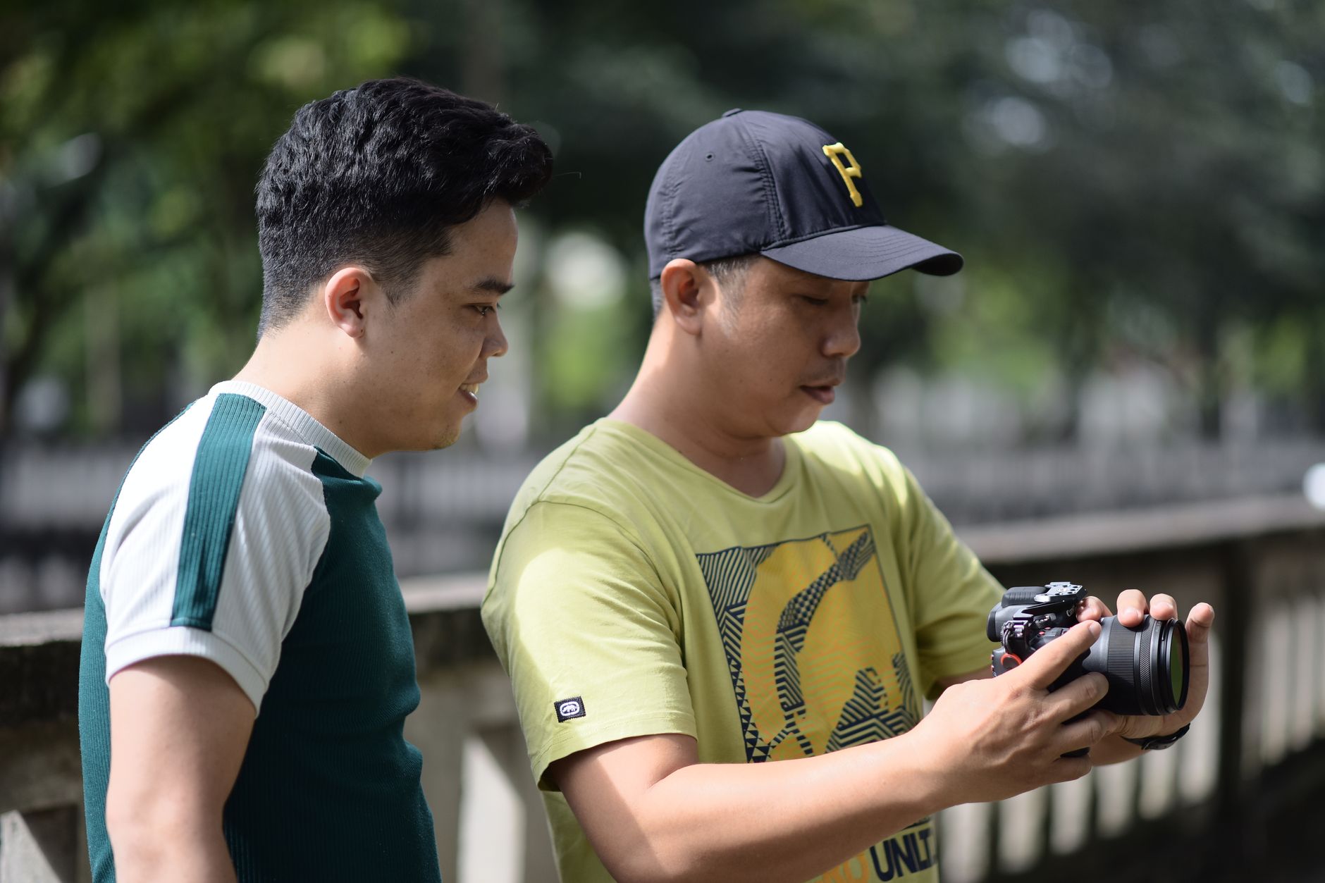 CJC 1295 Ipamorelin Review: Benefits for Americans 2 Two men standing outside, reviewing photos on a DSLR camera on a sunny day.