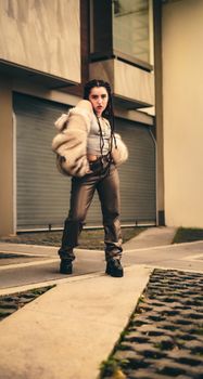 Trendy woman in fashionable attire poses confidently in a modern city environment.