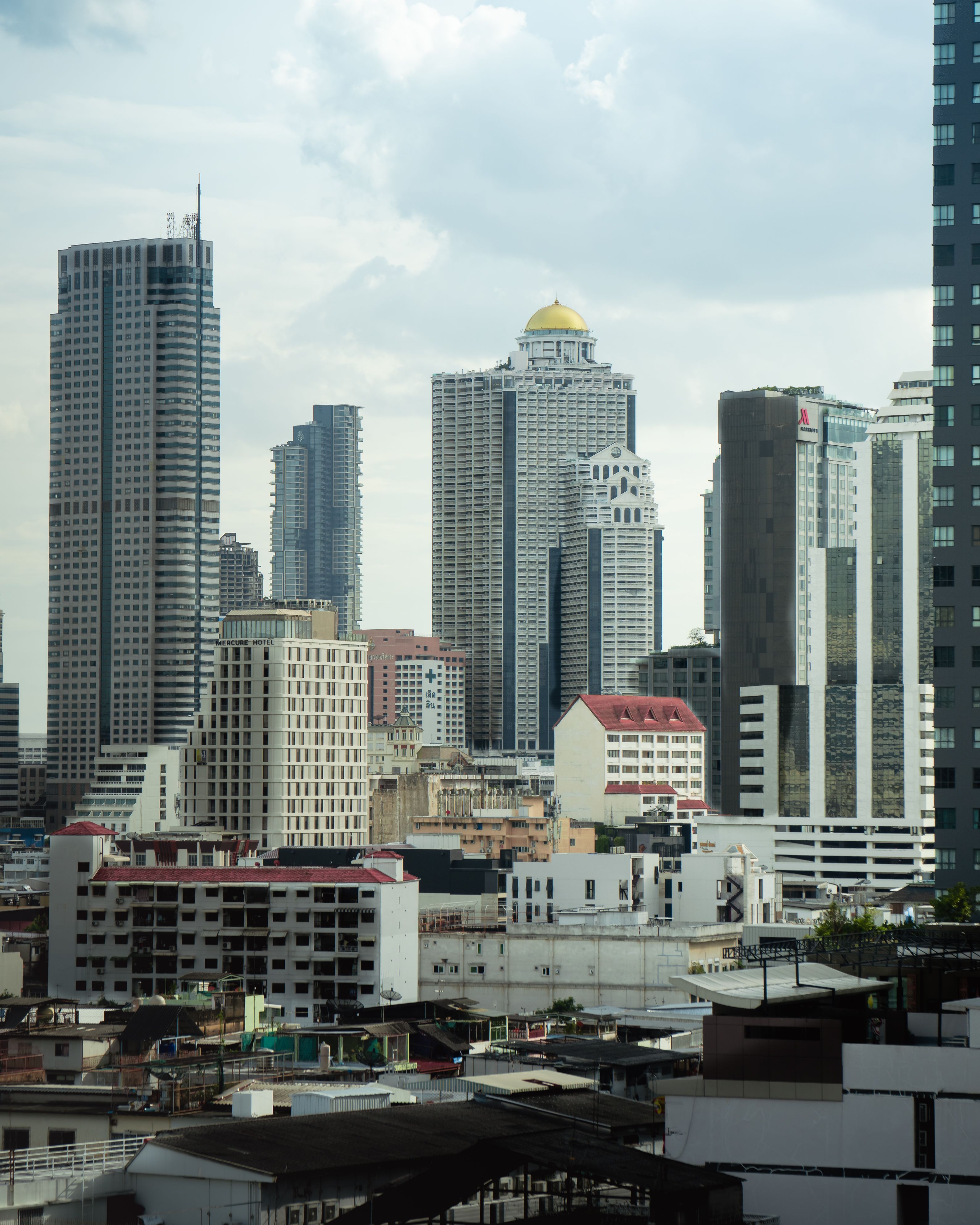 A stunning view of Bangkok's modern skyline featuring iconic skyscrapers under a cloudy sky.