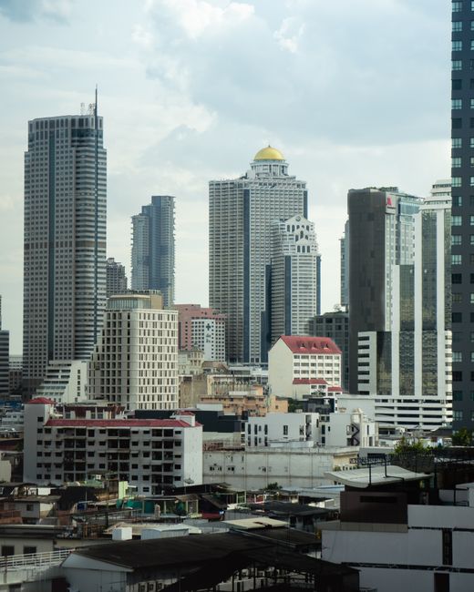 A stunning view of Bangkok's modern skyline featuring iconic skyscrapers under a cloudy sky.