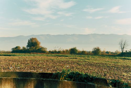 Free Peaceful rural field with distant mountains under a clear sky. Stock Photo