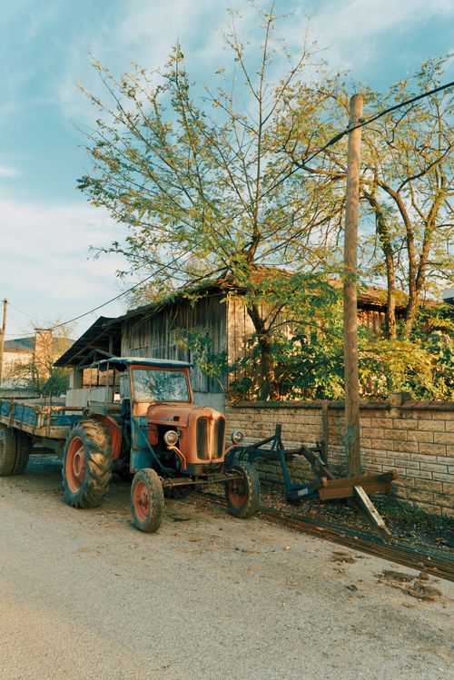 Free Vintage tractor parked beside a barn illustrates rural farming life during autumn. Stock Photo