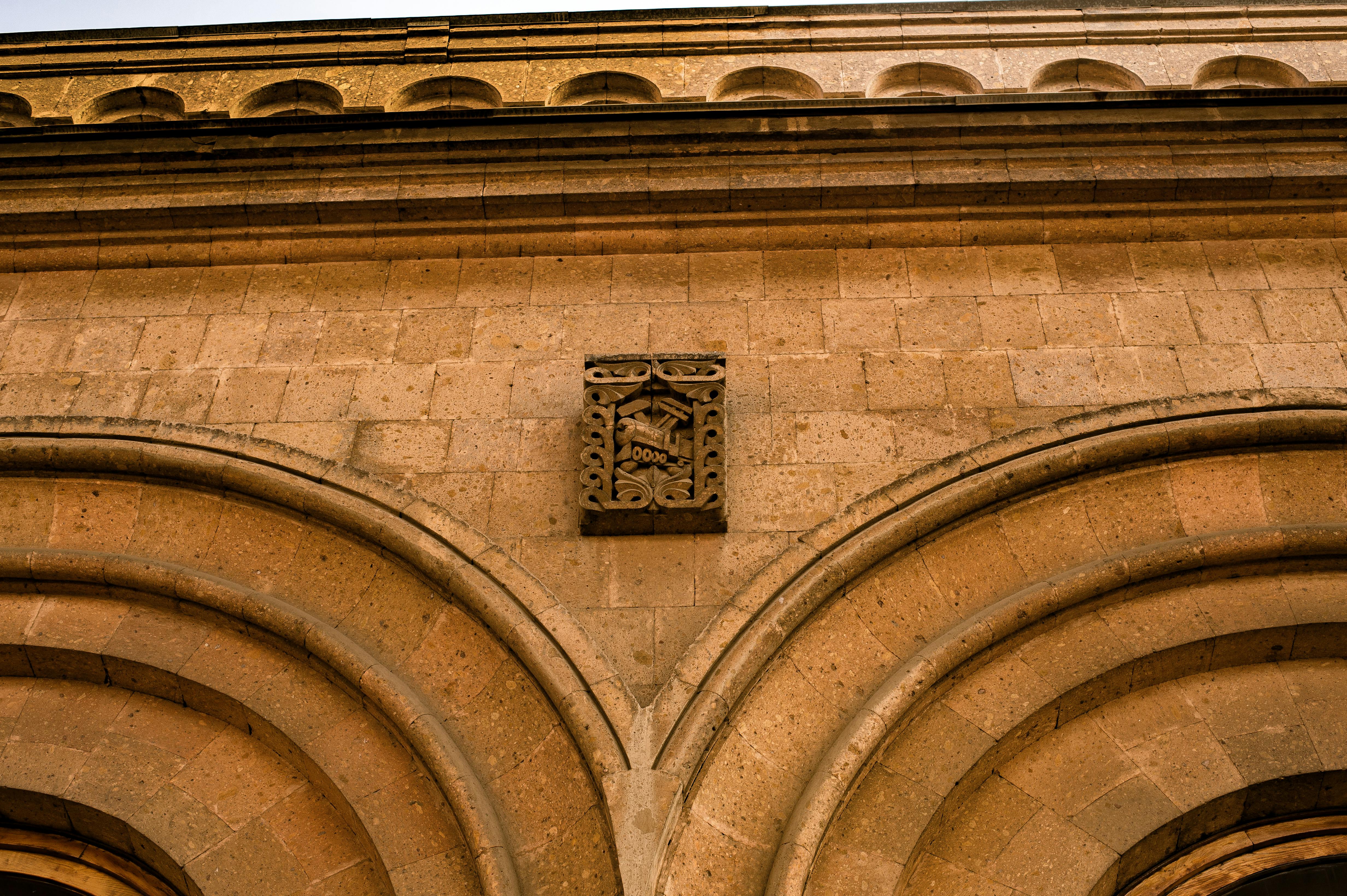 Gratis Nærbilde av den historiske bygningens detaljerte murverk med buet design og dekorative elementer. Arkivbilde