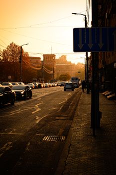 A bustling city street at sunset, showcasing traffic and rich autumn colors.