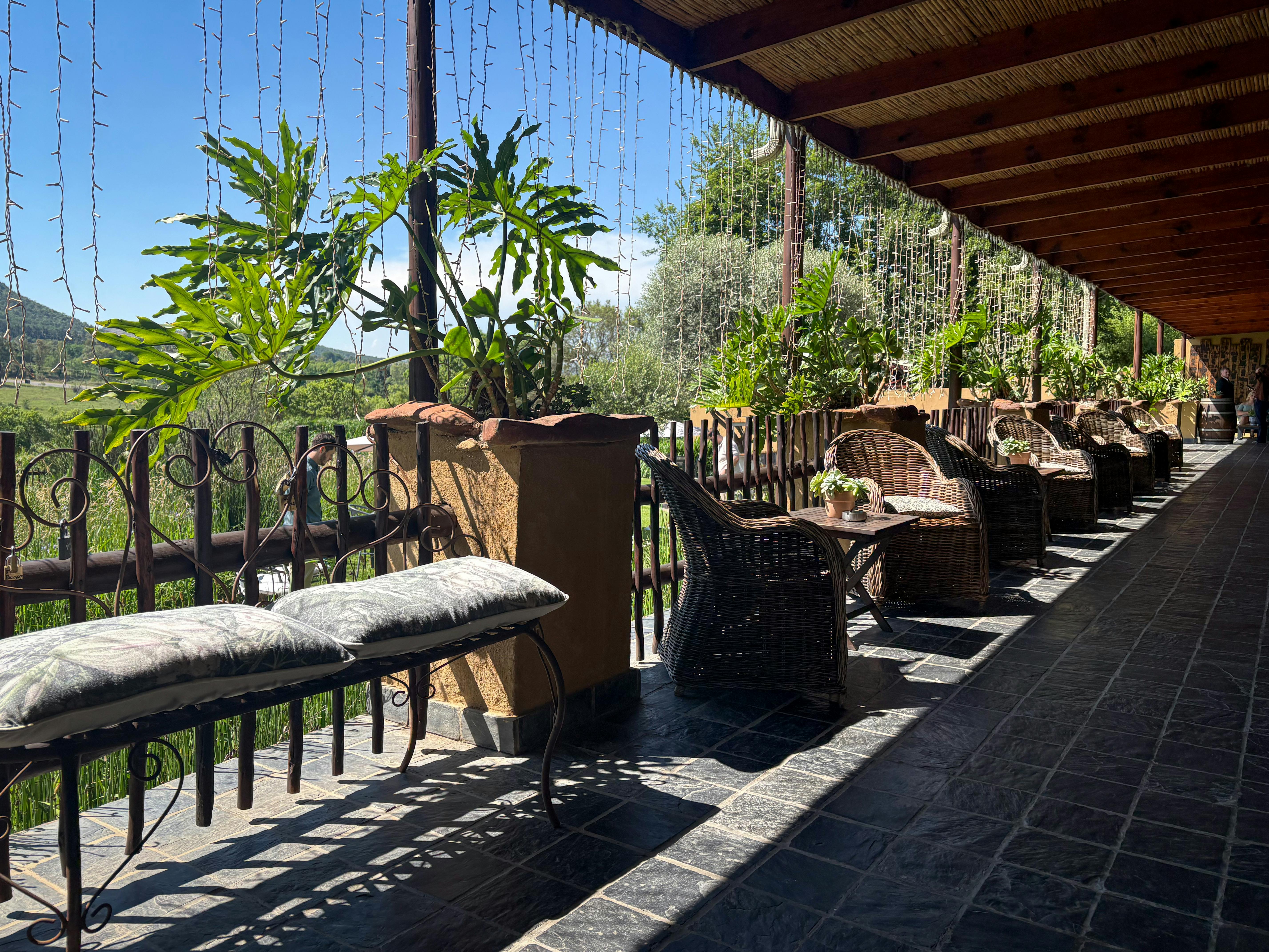 Beautiful outdoor patio with wicker chairs and lush plants under a wooden roof.