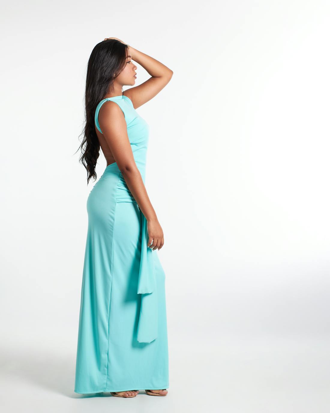 Woman posing in a long teal dress against a studio backdrop