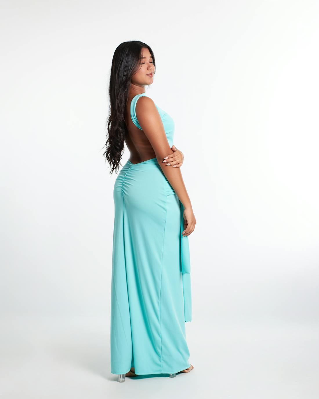 Side profile of a woman in an aqua gown with dramatic drape