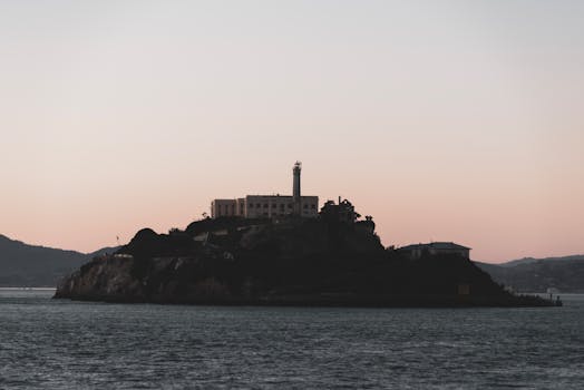 Scenic view of Alcatraz Island silhouetted against a twilight sky over the ocean.