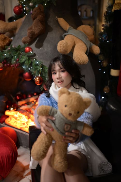 Free Woman holding teddy bear by a festive decorated fireplace, creating a warm and cozy atmosphere. Stock Photo