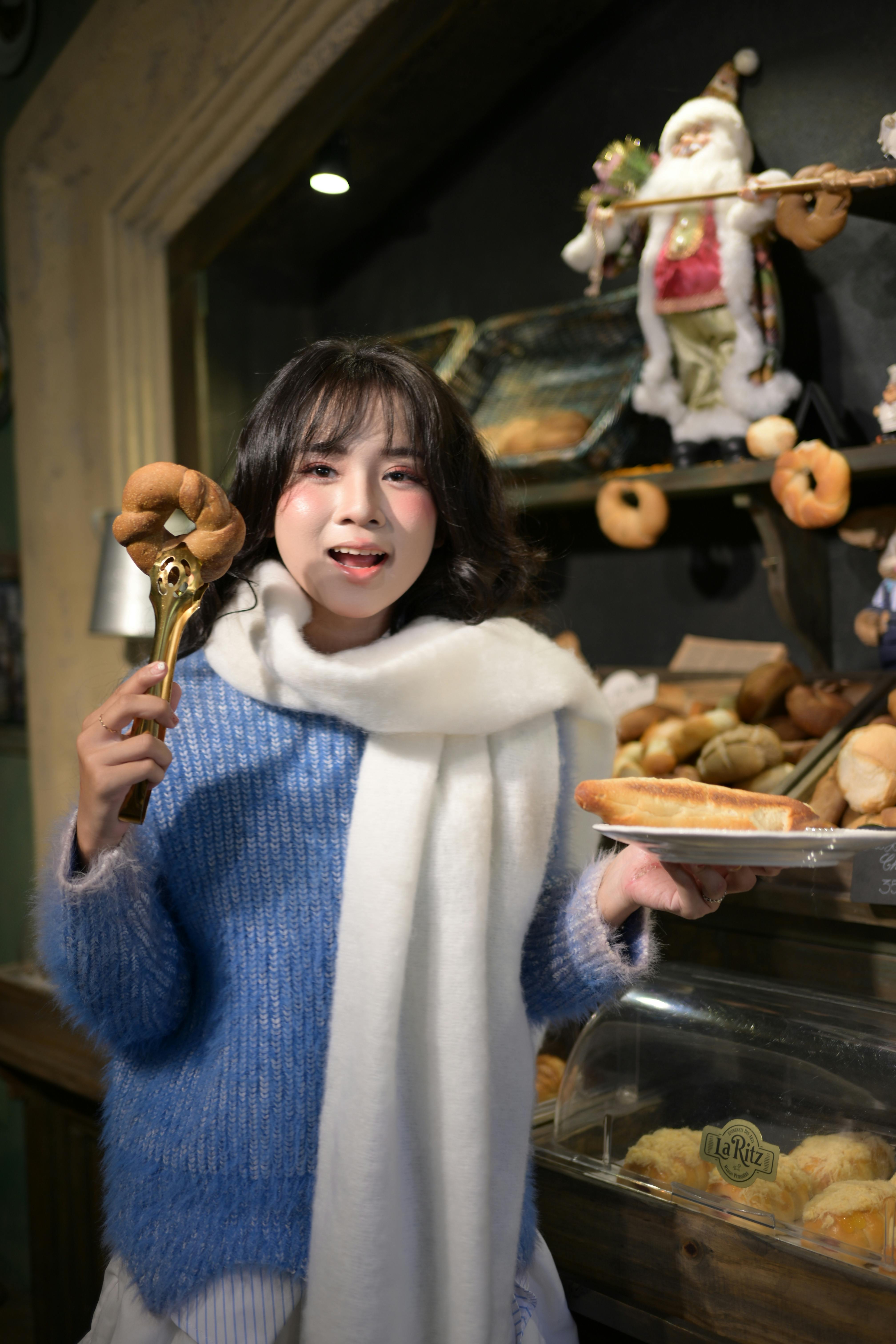 Woman in winter attire enjoys fresh pastries in a cozy bakery setting, exuding joy and warmth.