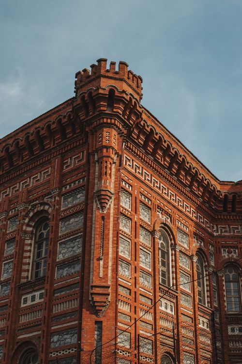 Free A stunning view of a historic red brick building with intricate designs under clear blue skies. Stock Photo