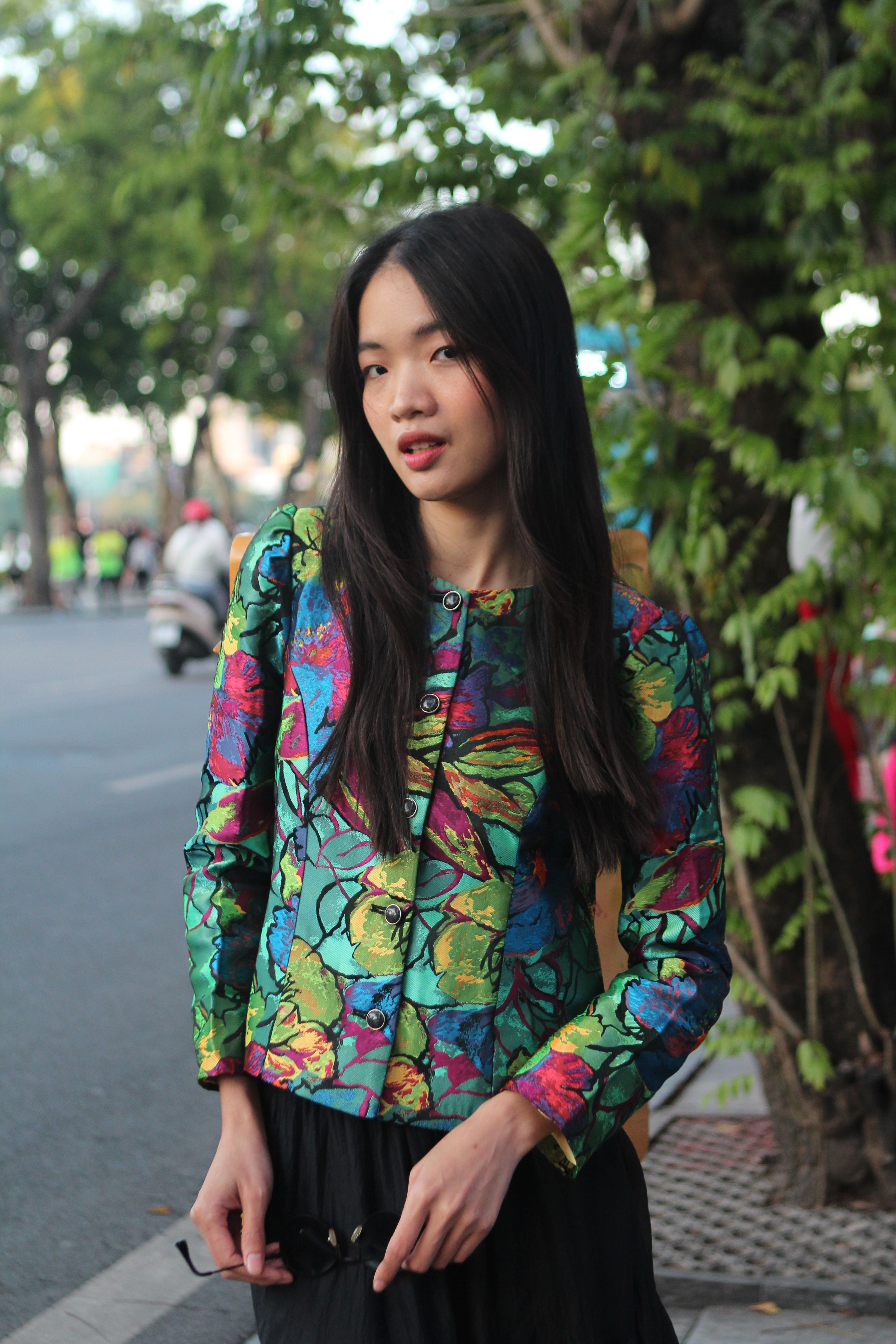 Portrait of a young woman in vibrant attire with a street background.