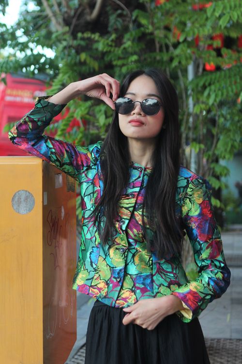 Free Stylish woman in floral jacket and sunglasses poses confidently outdoors. Stock Photo