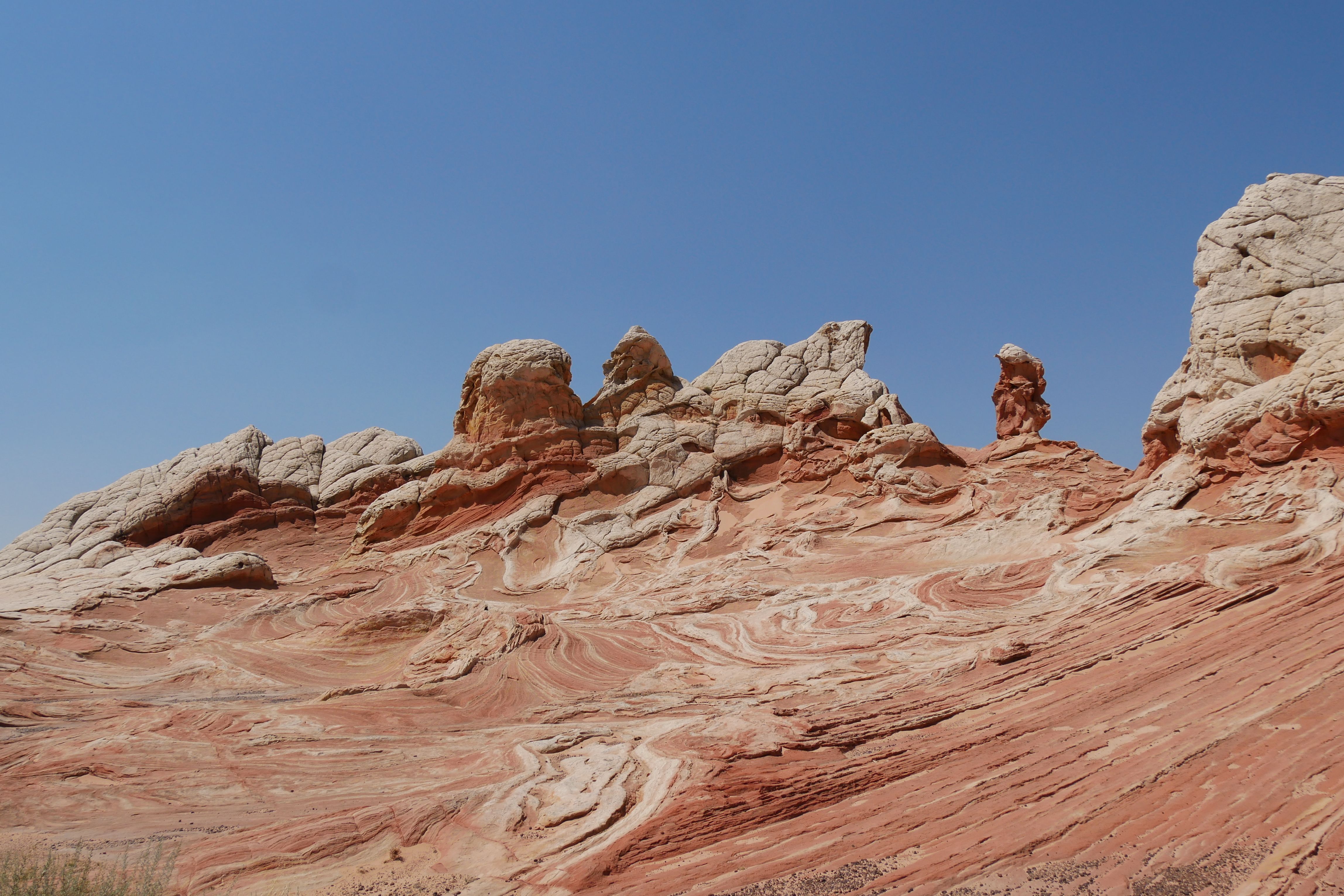 Stunning landscape of red rock formations under a clear blue sky, showcasing natural beauty and erosion patterns.