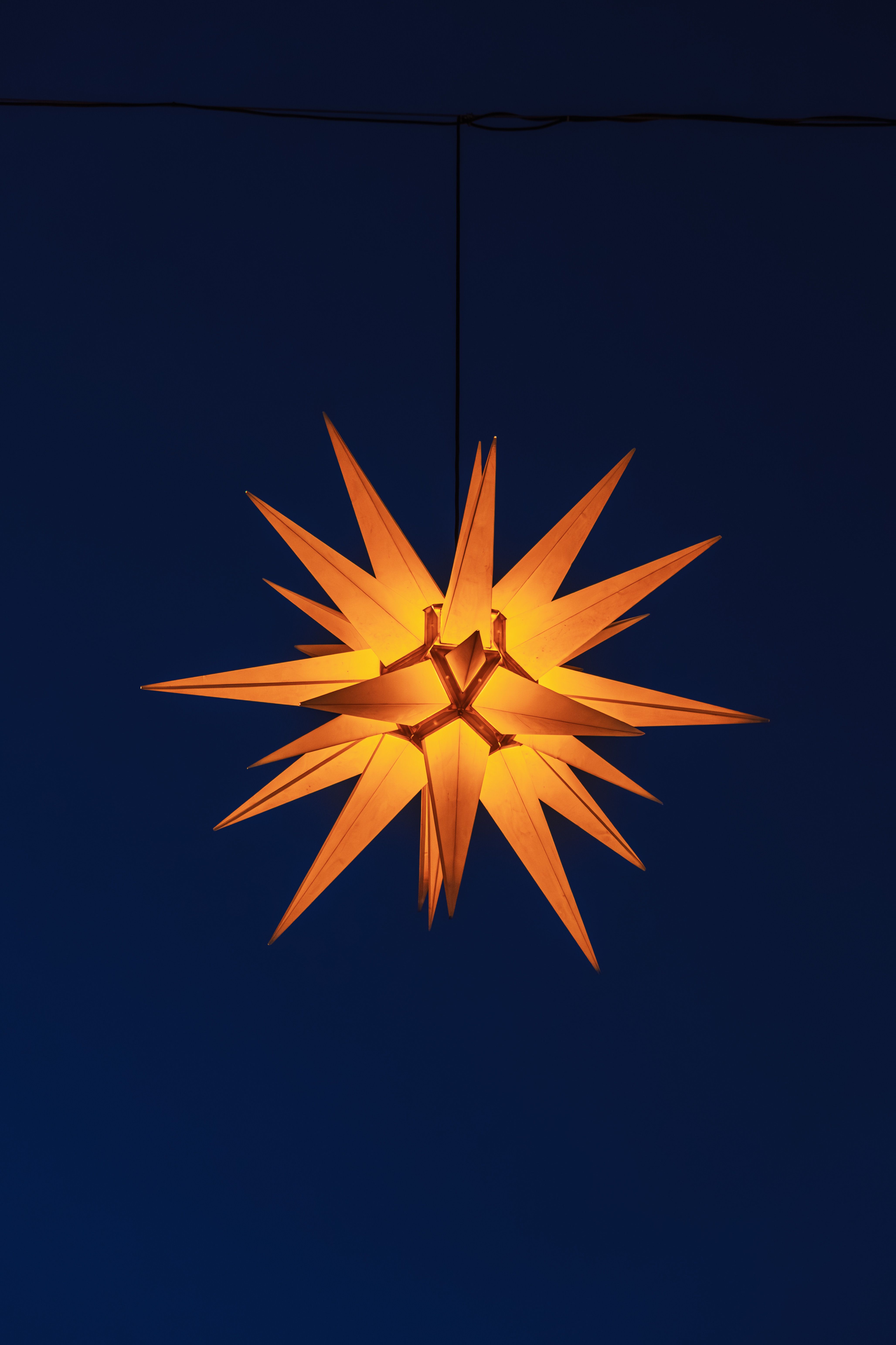 A glowing star decoration shines warmly against the deep blue evening sky, evoking festive holiday feelings.