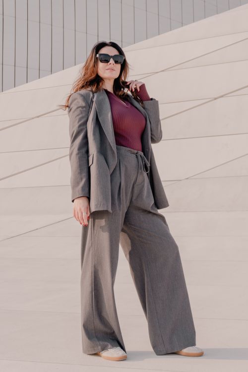 Free Fashionable woman in a gray suit poses confidently on modern architectural steps. Stock Photo