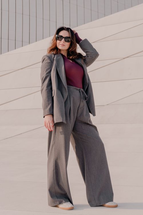 Free Stylish woman in a gray suit posing against modern architecture outdoors. Stock Photo