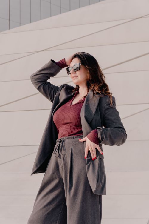 Free Confident woman in sunglasses and elegant suit posing against a contemporary architectural background. Stock Photo