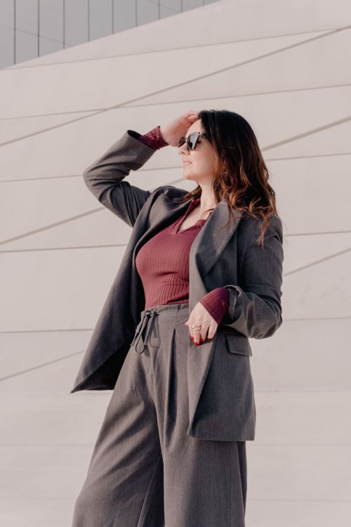 Free Stylish woman in a gray suit and sunglasses posing outdoors, capturing modern urban fashion. Stock Photo