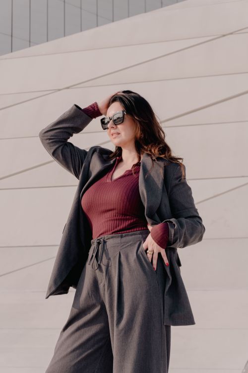 Free Stylish woman in sunglasses wearing a trendy outfit poses confidently outdoors against a modern backdrop. Stock Photo
