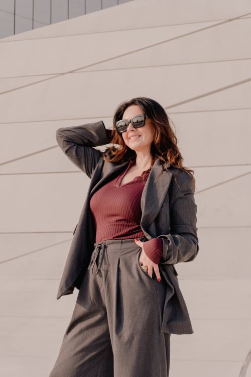 Free Confident woman in trendy outfit posing outdoors against a modern geometric wall. Stock Photo