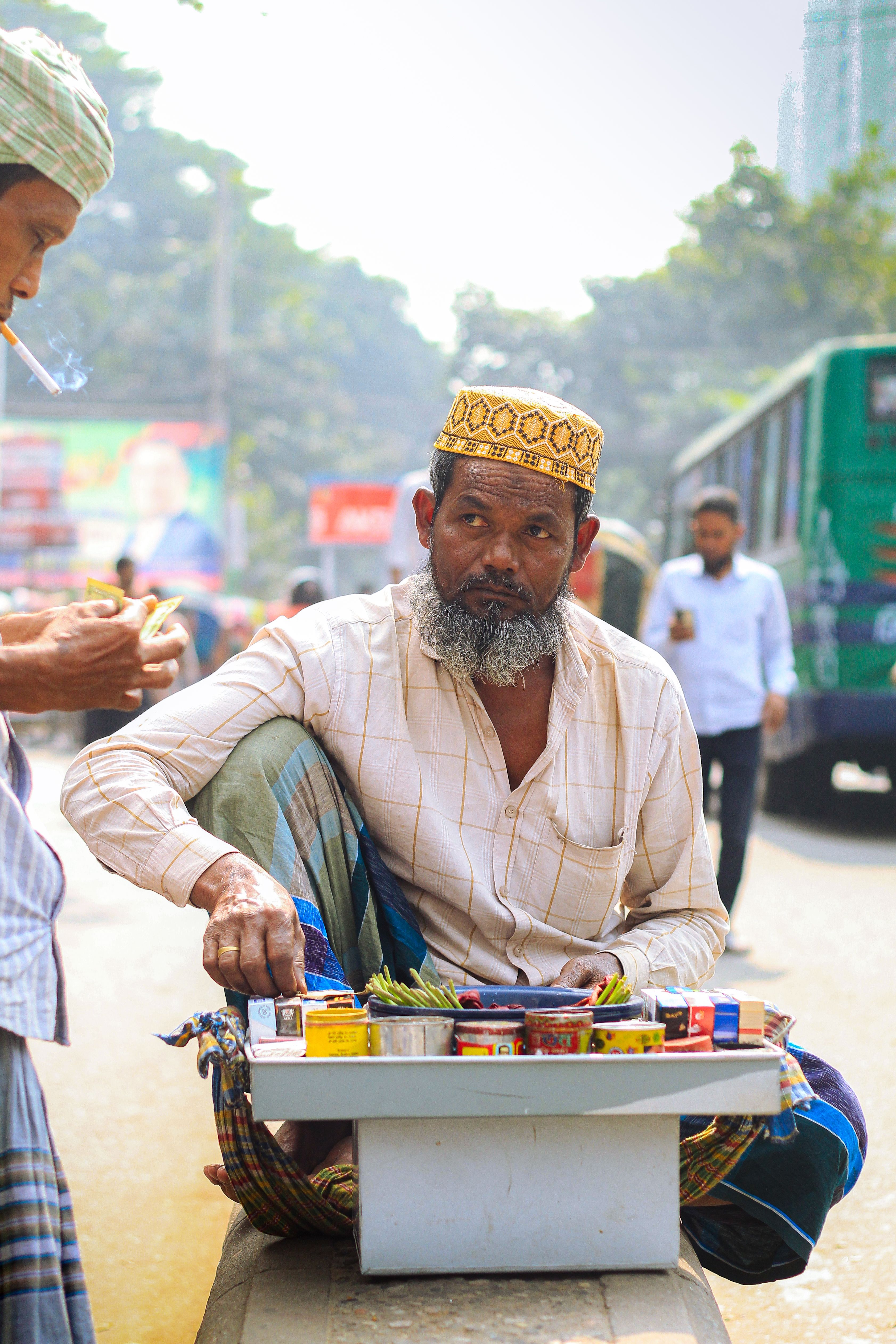 A street vendor in Dhaka selling betel leaves on a busy city street.