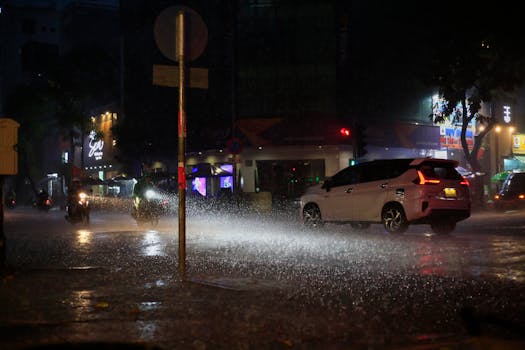 Nighttime rain pours down on a busy street in Ho Chi Minh City, Vietnam, capturing urban life.