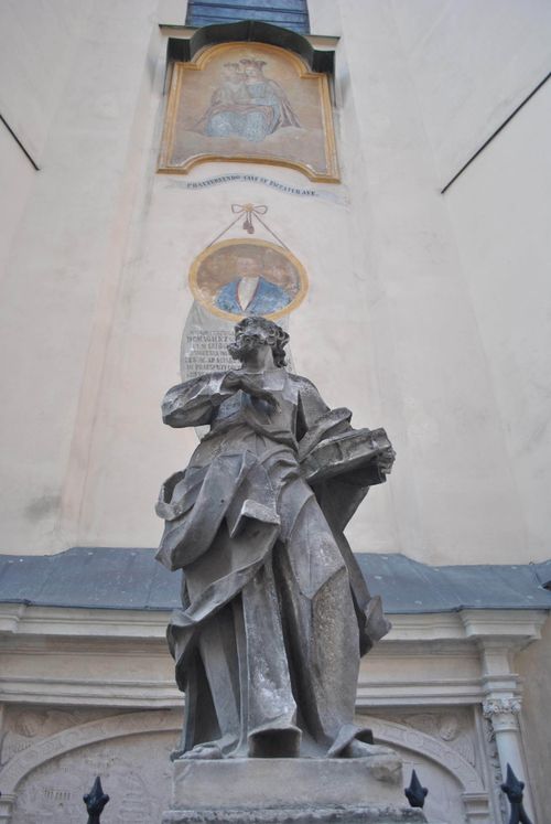 Free A detailed stone statue in front of a historic building with wall art. Stock Photo
