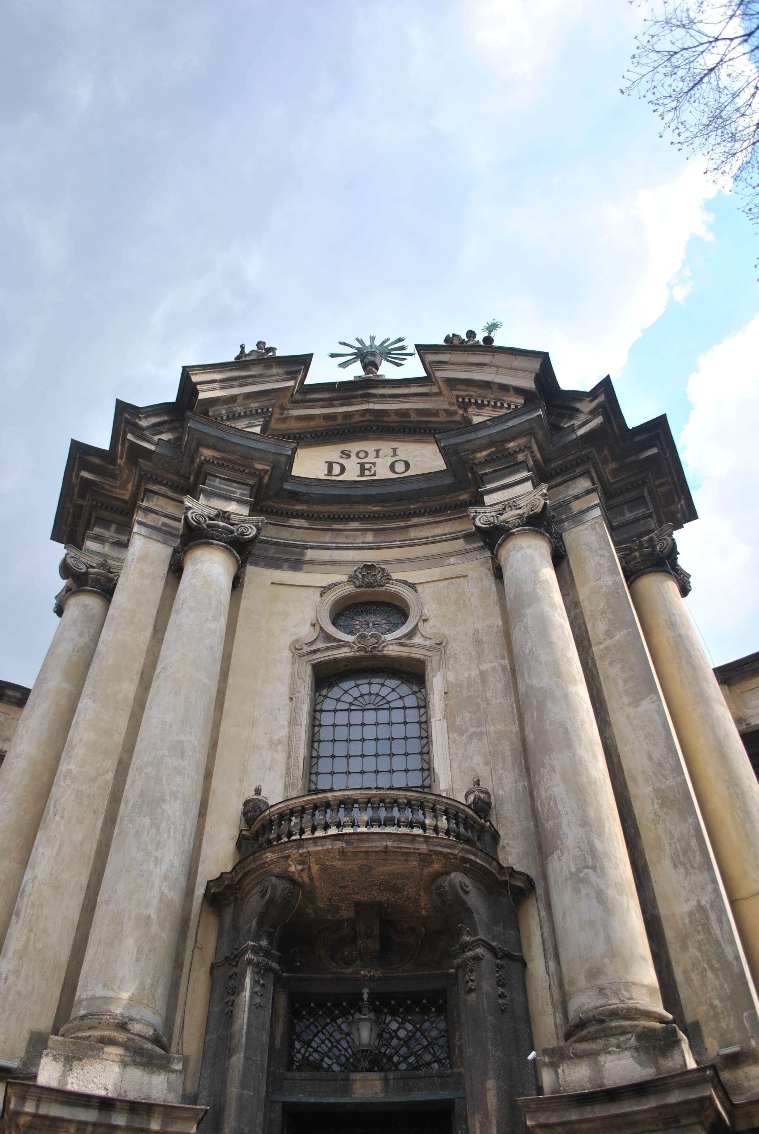 Close-up of an ornate Baroque-style church facade with prominent columns and Soli Deo inscription.