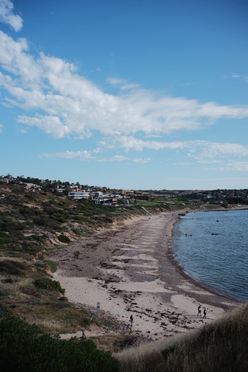 Free Stunning coastal view with a sandy beach and cliffside homes under a clear blue sky. Stock Photo