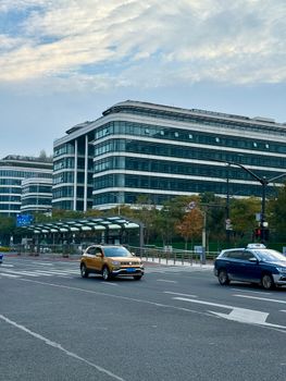Street view of modern office buildings in Shanghai with passing cars.