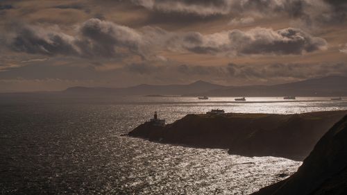 Free Explore the scenic Irish coastline featuring a lighthouse and stunning ocean views at sunset. Stock Photo