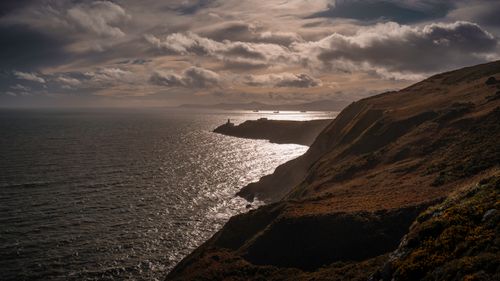 Free A stunning view of the Irish coastline with a lighthouse under dramatic skies. Stock Photo