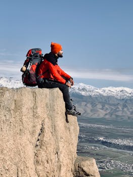 一名孤独的徒步旅行者身穿红色夹克，坐在悬崖上欣赏伊拉克的全景