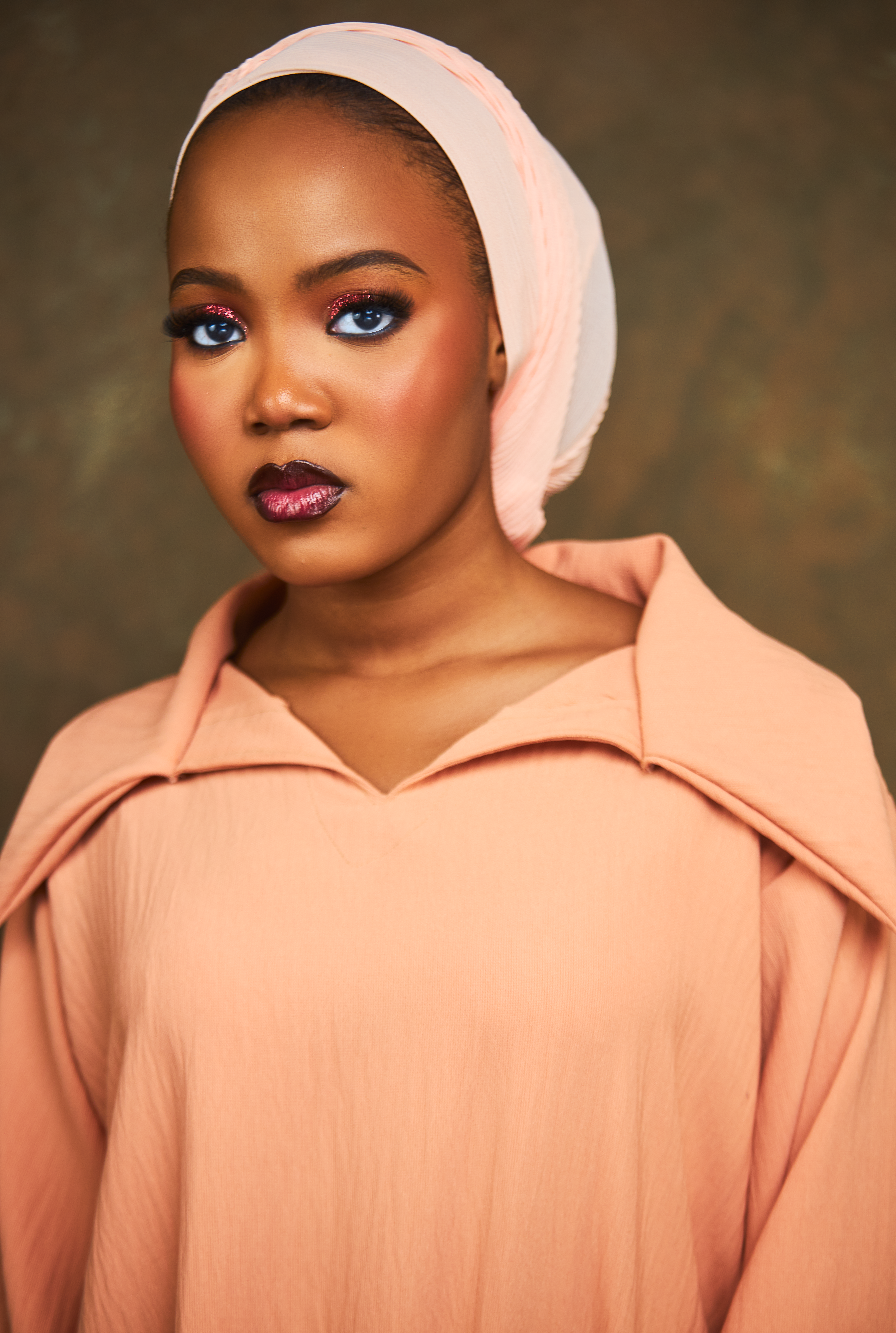 Striking portrait of a woman in peach dress with a serene expression.